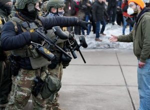 Agente federal e manifestante gesticulam durante protesto contra o assassinato de Renee Nicole Go...