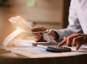 closeup-economist-using-calculator-while-going-through-bills-taxes-office-675x450