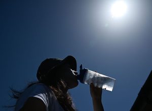 Mulher tenta se refrescar bebendo água durante uma onda de calor em Londres, Reino Unido, em 26 ...